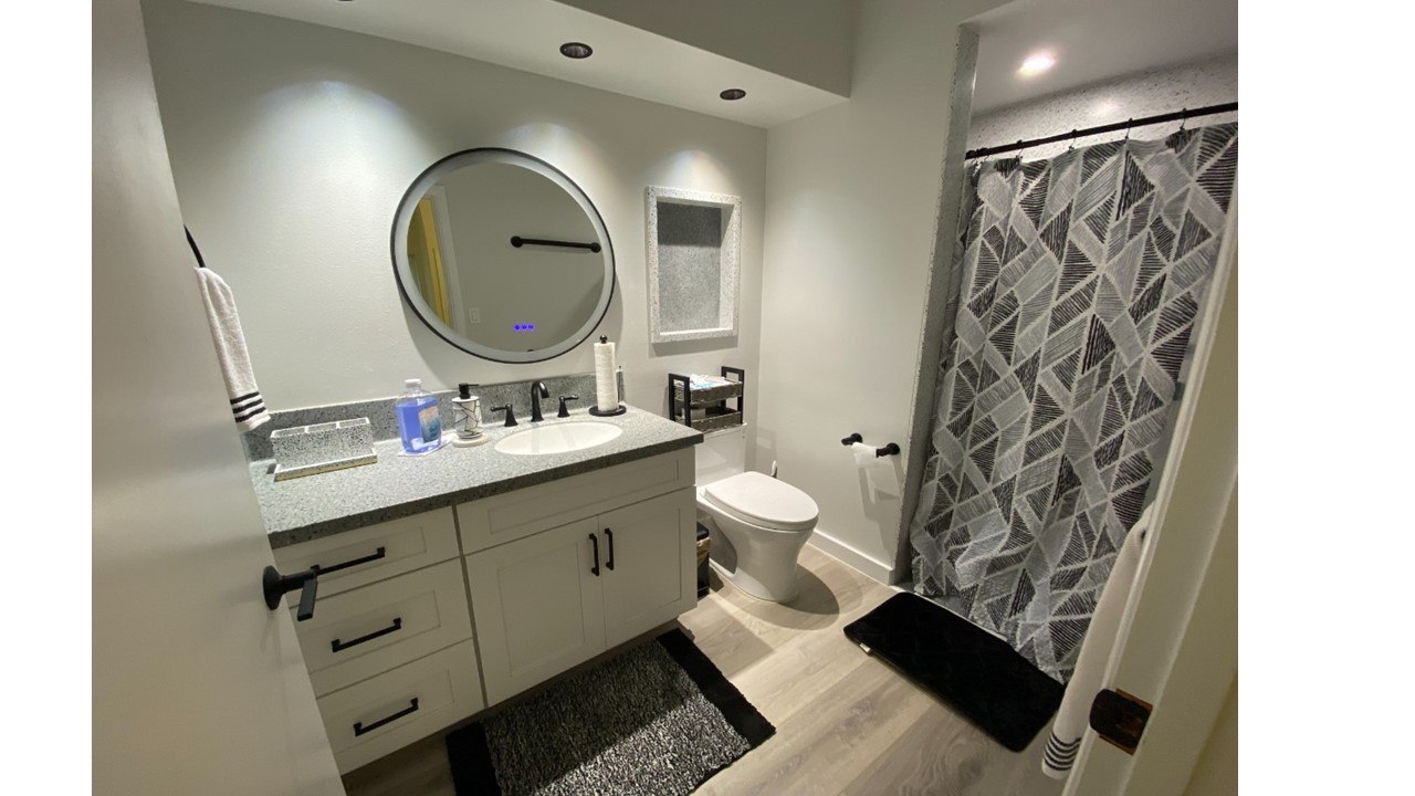 A bathroom with a toilet, sink, and mirror.